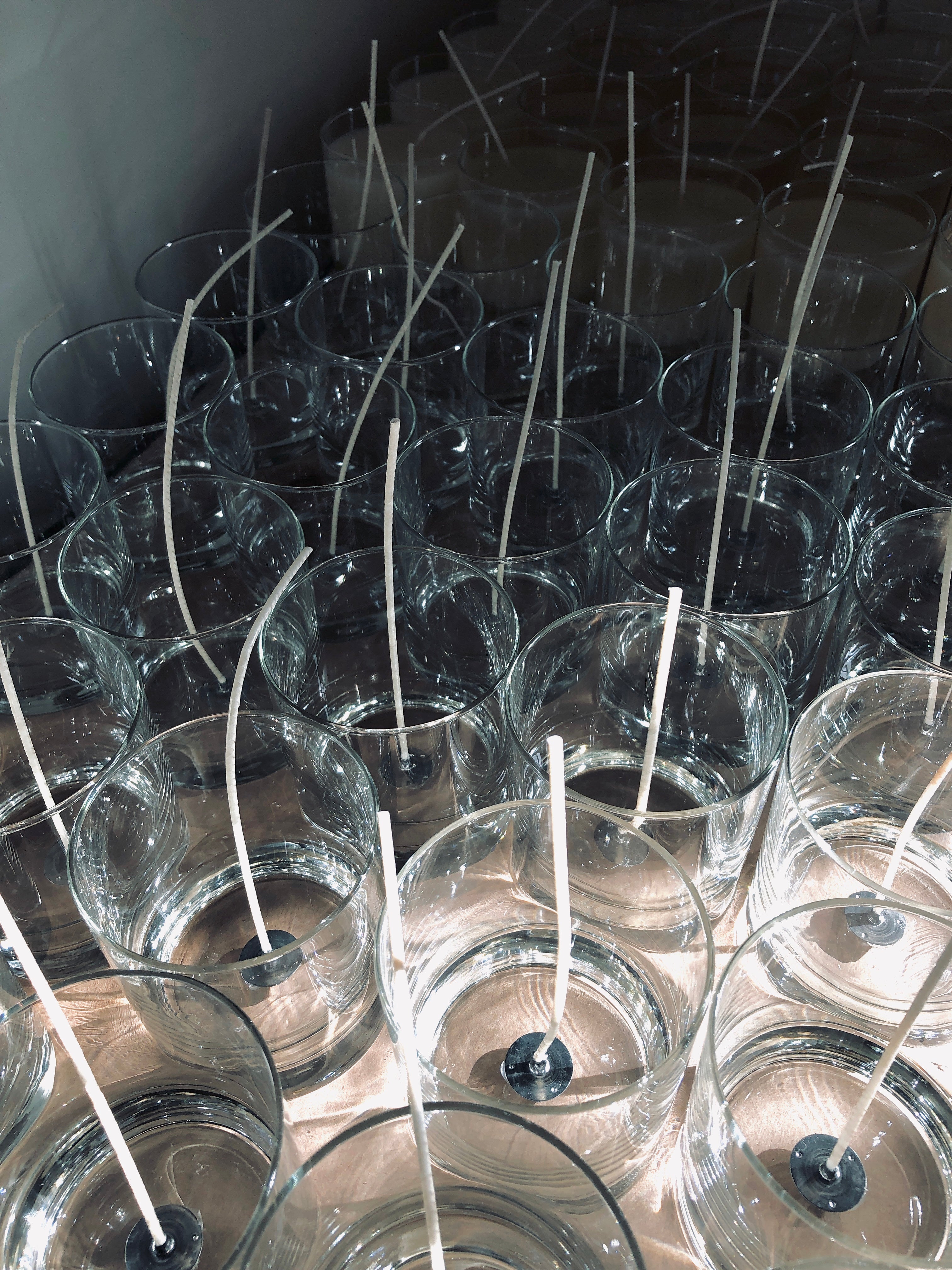 Empty transparent candle jars with cotton wicks placed in center of jars